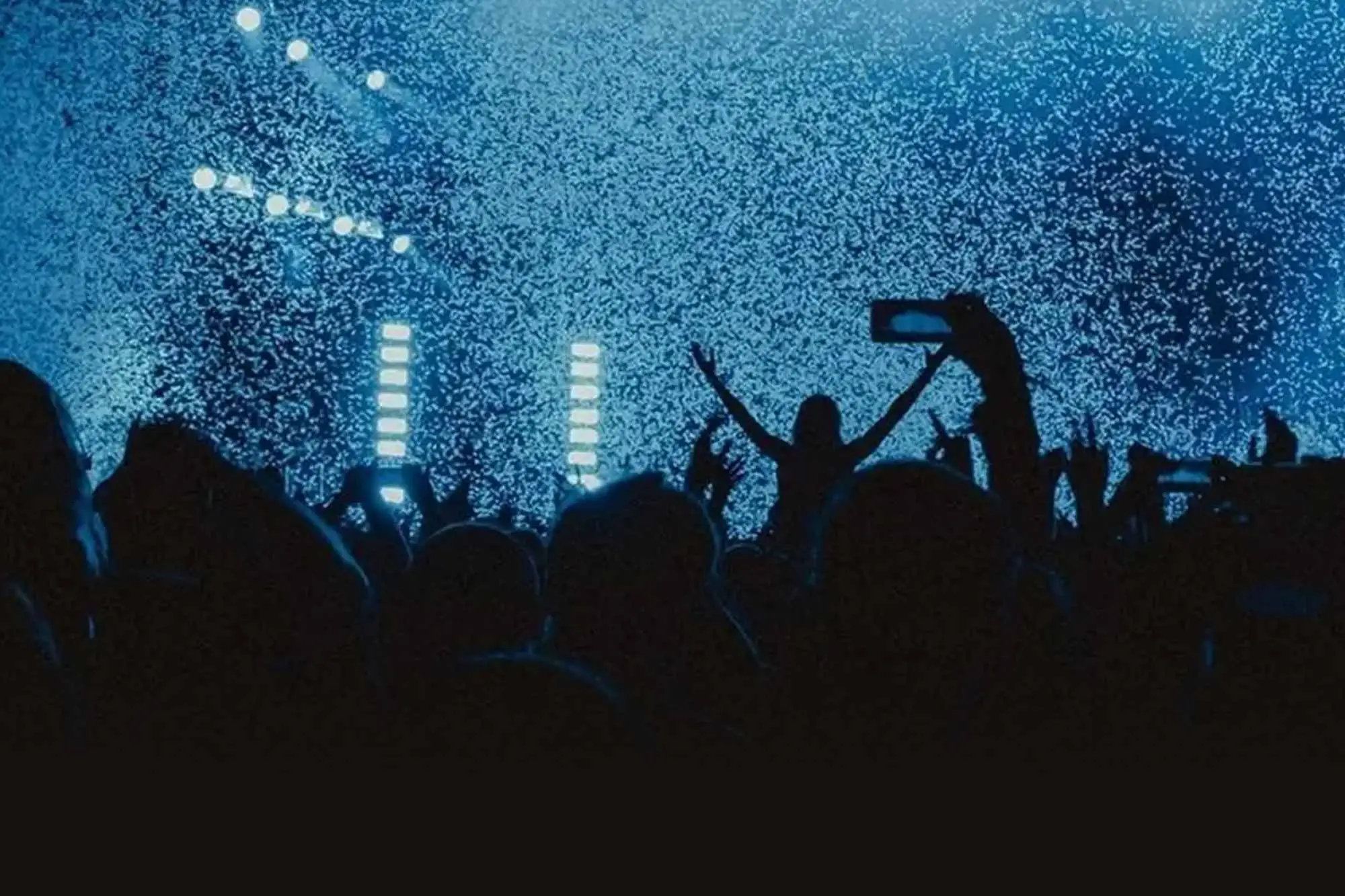 A large crowd at a concert waiting on the performing to arrive on stage