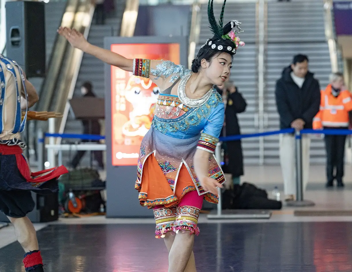 A photo of a woman performing a traditional Chinese dance at Belfast Grand Central Station.