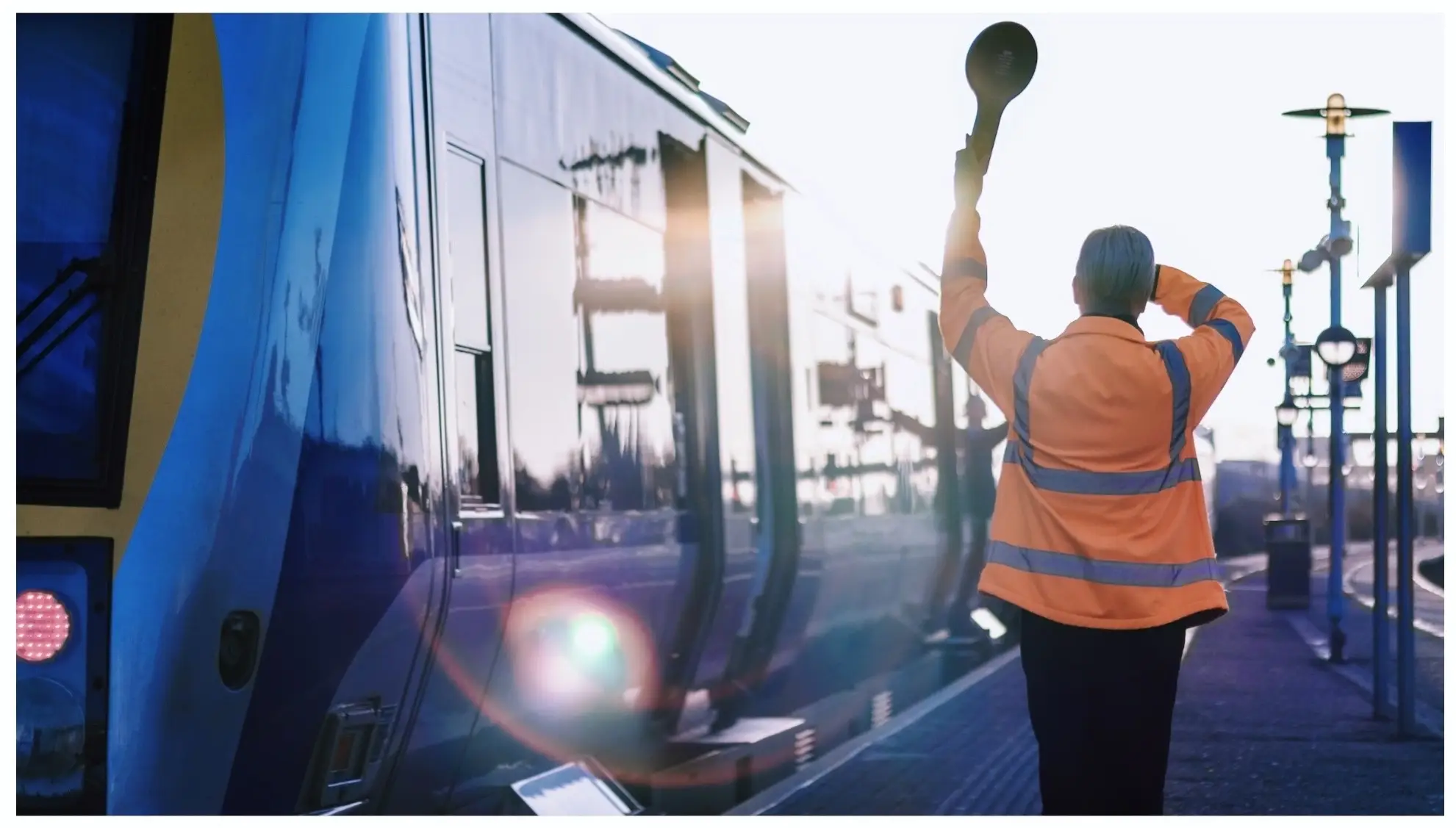 A photo of a Translink staff member signalling to a departing train